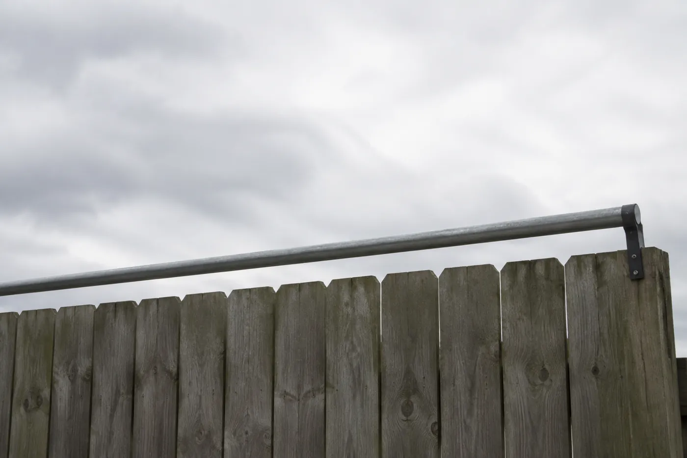 A garden fence topped with an inward facing roller bar