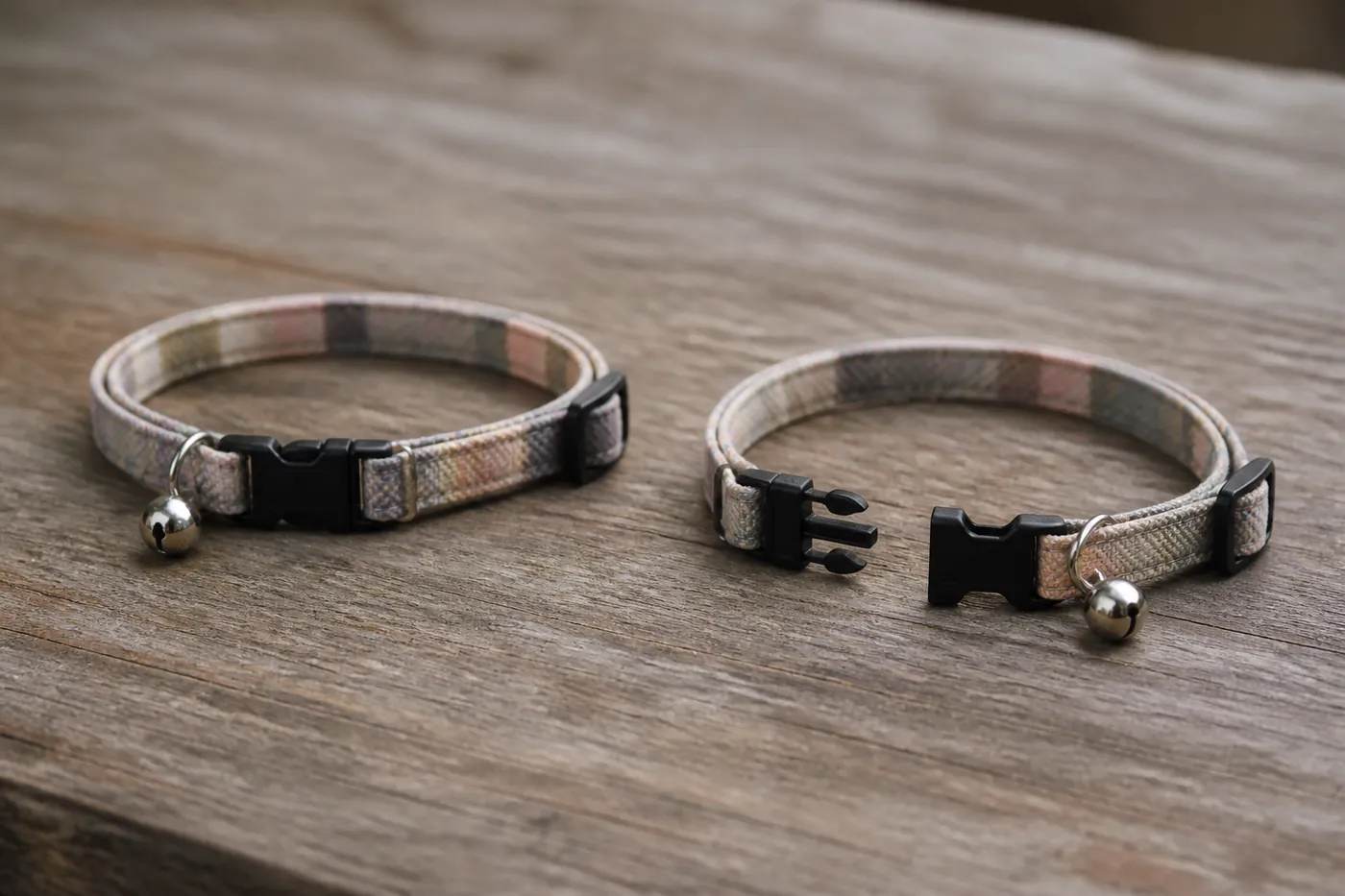 A breakaway collar buckle shown open beside a closed one on a wooden surface