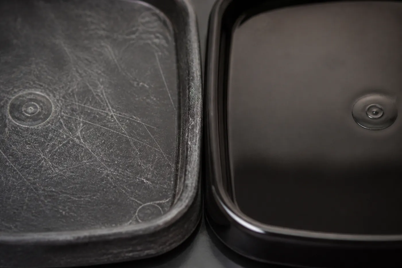 A scratched and scored plastic tray base beside a smooth new one