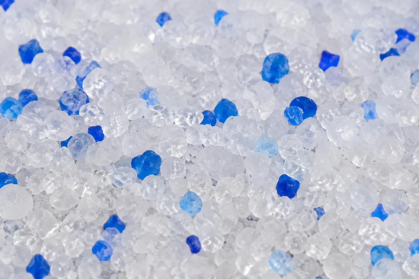 Close view of translucent white silica gel litter beads with scattered blue granules