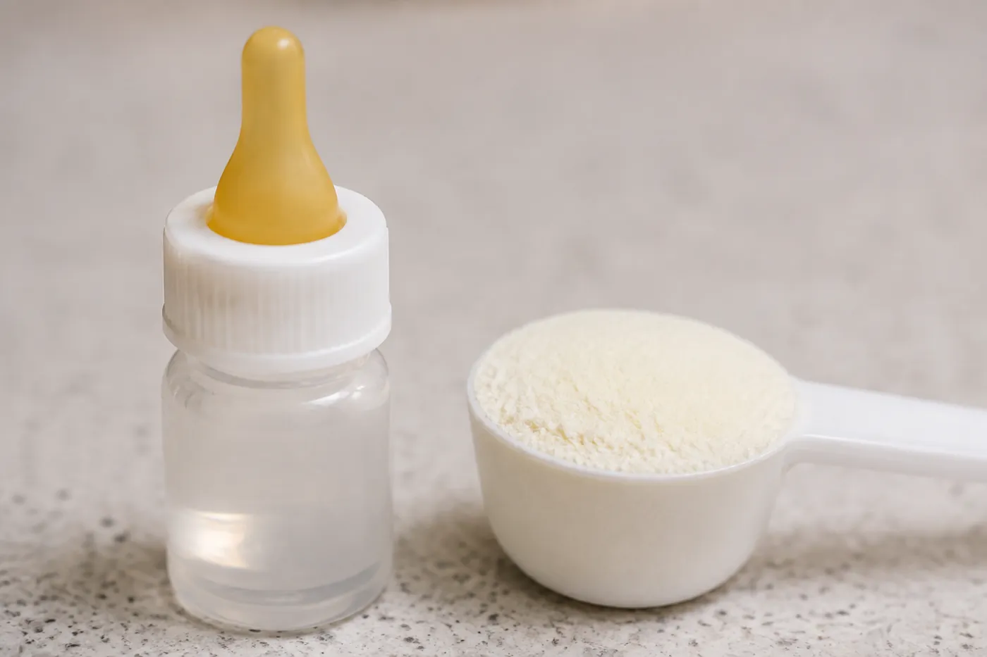 A small nursing bottle and a measuring scoop of milk replacer powder